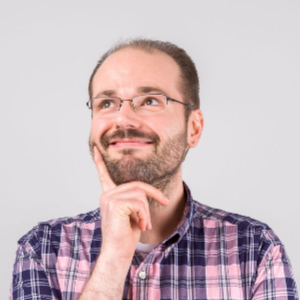 Photo of Steve posed with a finger on his cheek looking up and to the side while smiling and wearing a customary plaid shirt.